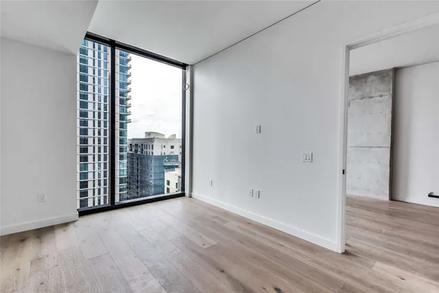 a view of an empty room with wooden floor and a window