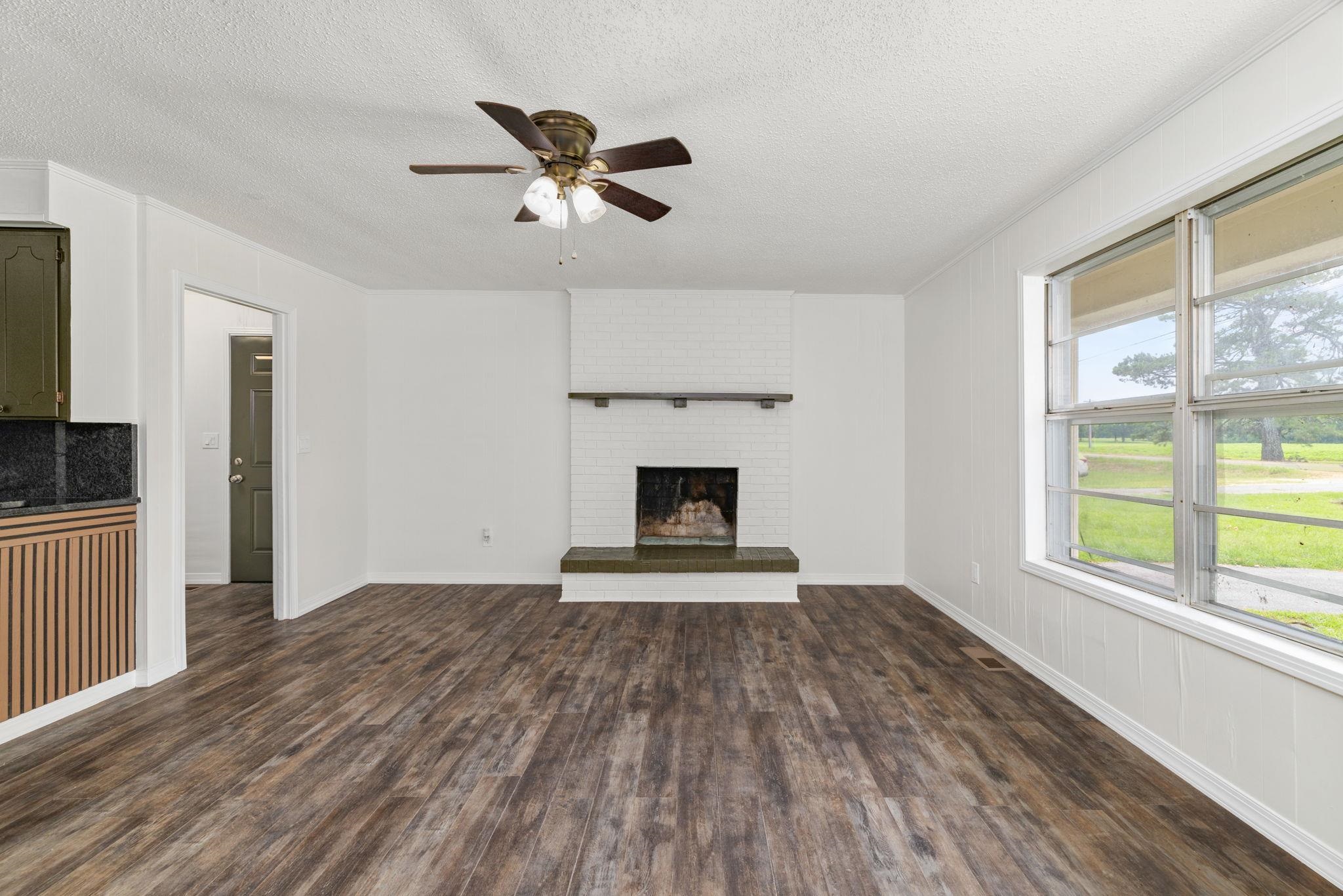 217 Red Bay Road Golden, MS 38847 - Photo 5 of 33 Living area featuring wood-finish flooring, a white brick fireplace, and a ceiling fan