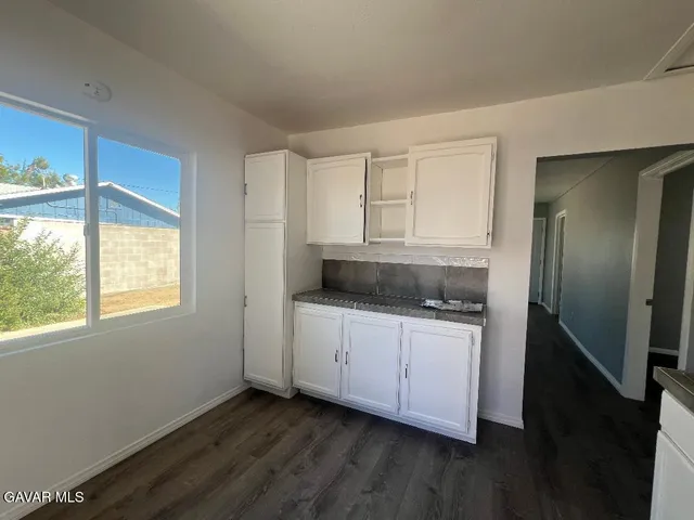 a kitchen with granite countertop white cabinets and a wooden floor