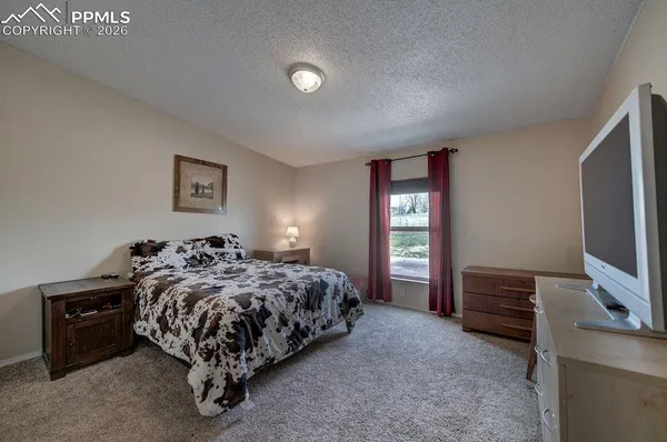 a bedroom with a bed and a flat tv screen on a dresser
