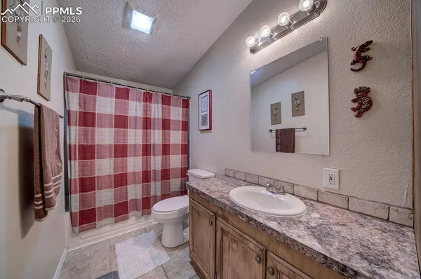 a bathroom with a granite countertop sink a toilet a mirror and shower