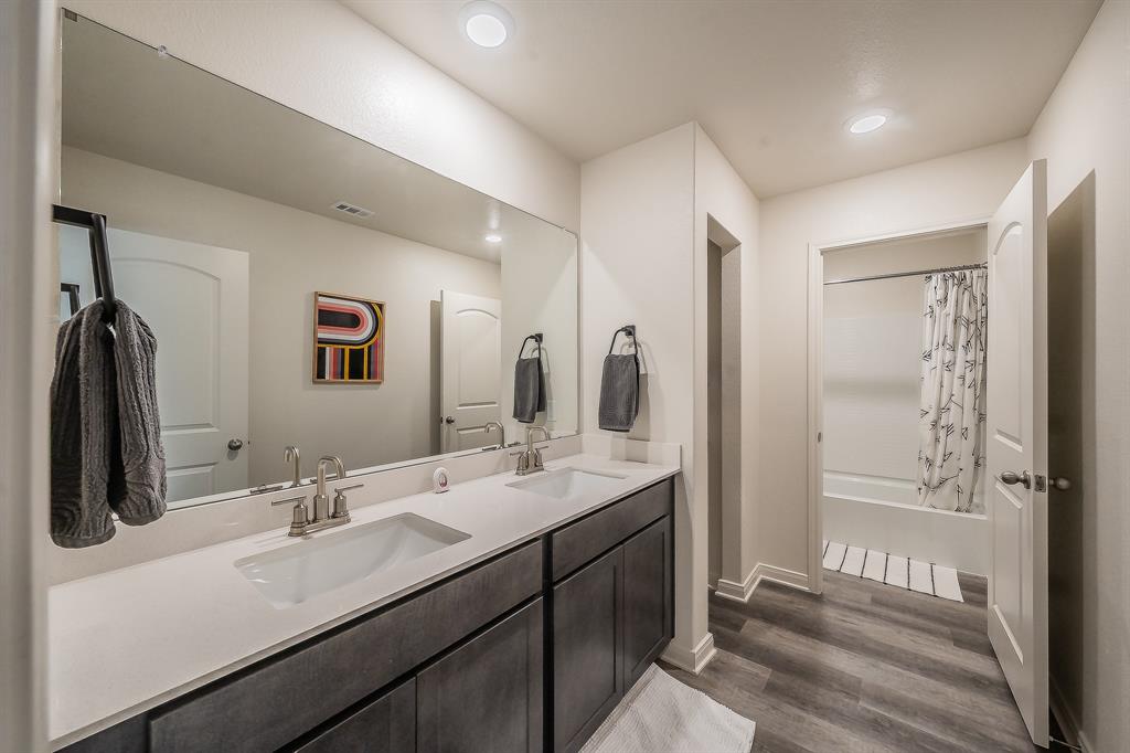 8125 White Sulphur Road Ponder, TX 76259 - Photo 24 of 38 Bathroom featuring a dual vanity with undermount sinks, light-toned countertops, and dark wood-finish cabinetry