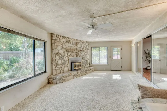 a view of a livingroom with a chandelier fan and kitchen view
