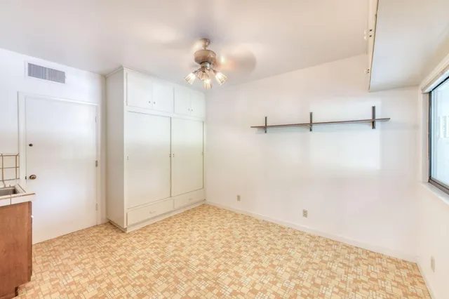 an empty room with windows and refrigerator