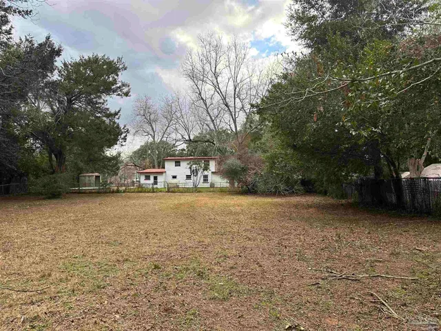 a view of a field with trees in front of house