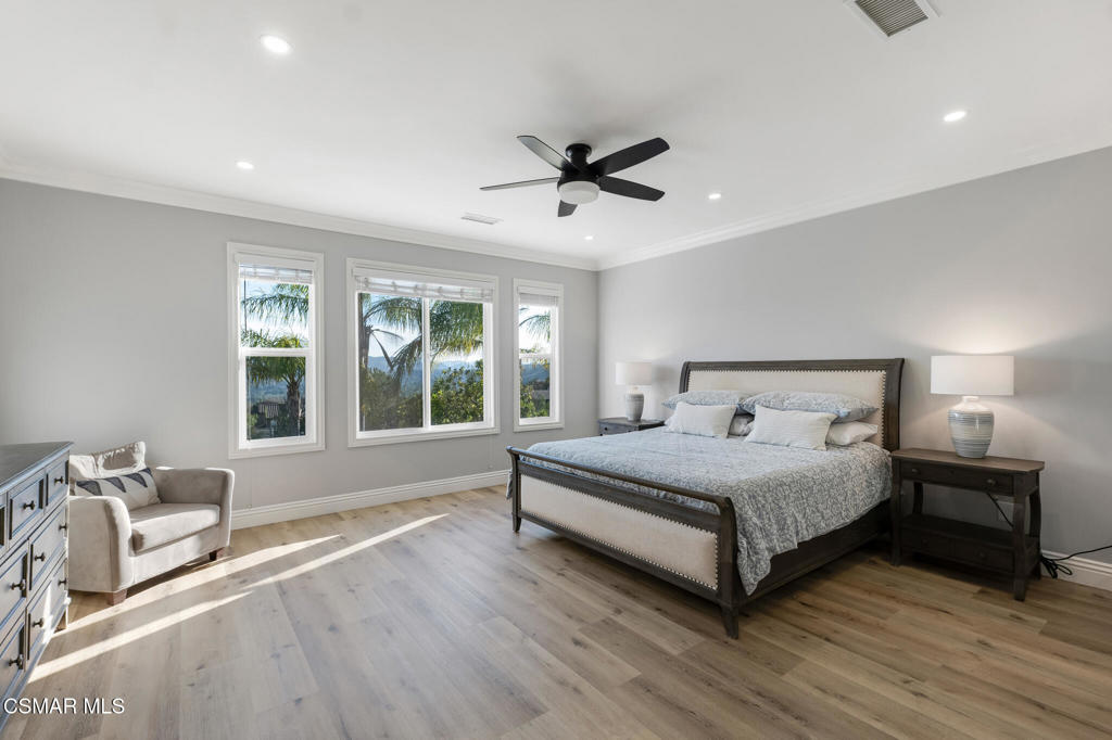 6140 Deerhill Road Oak Park, CA 91377 - Photo 22 of 72 a bedroom with a large bed a chandelier and windows