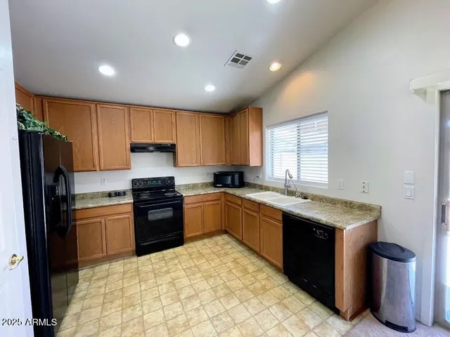 a kitchen with stainless steel appliances granite countertop a stove sink refrigerator and cabinets