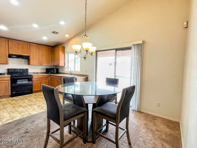 a dining area with stainless steel appliances kitchen island granite countertop a dining table chairs and a refrigerator