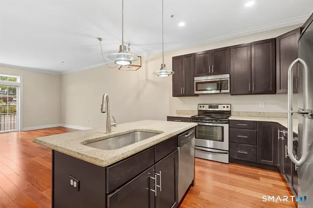 a kitchen with kitchen island granite countertop a sink stainless steel appliances and counter space