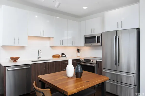 a kitchen with stainless steel appliances a table chairs microwave and refrigerator