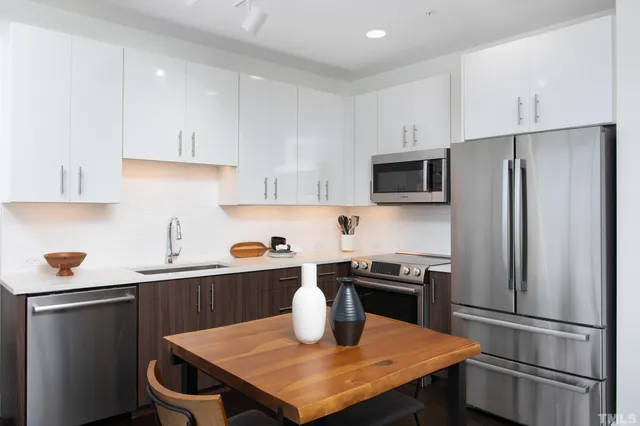 a kitchen with stainless steel appliances a table chairs microwave and refrigerator