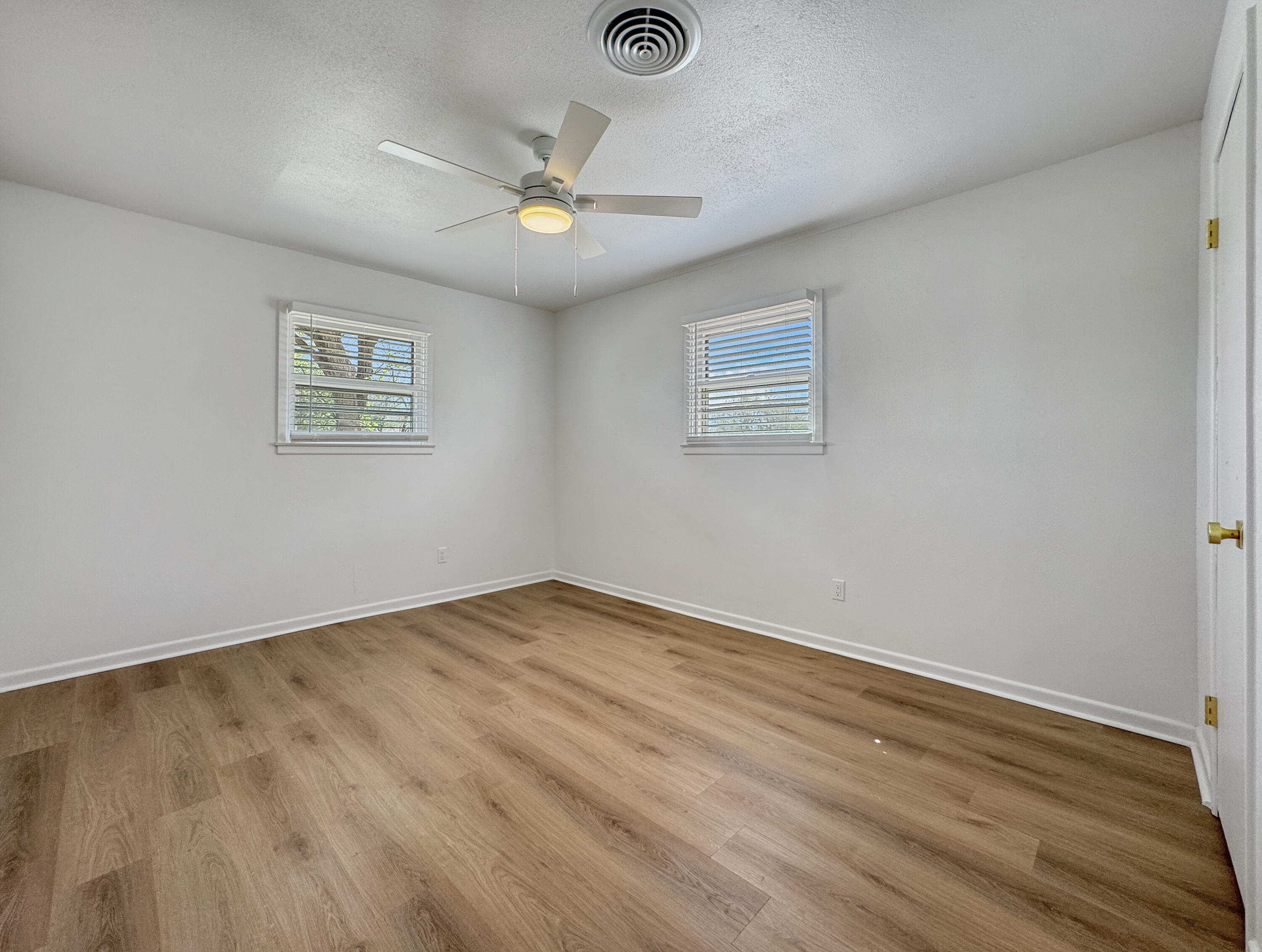 5502 8th Street Lubbock, TX 79416 - Photo 30 of 41 a view of an empty room with wooden floor and a ceiling fan