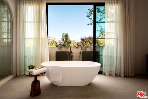 a white bath tub sitting in a bathroom next to a window