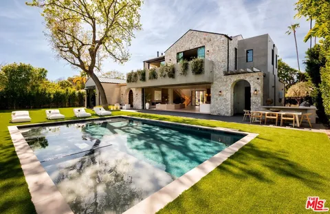 a view of swimming pool with outdoor seating and house in the background