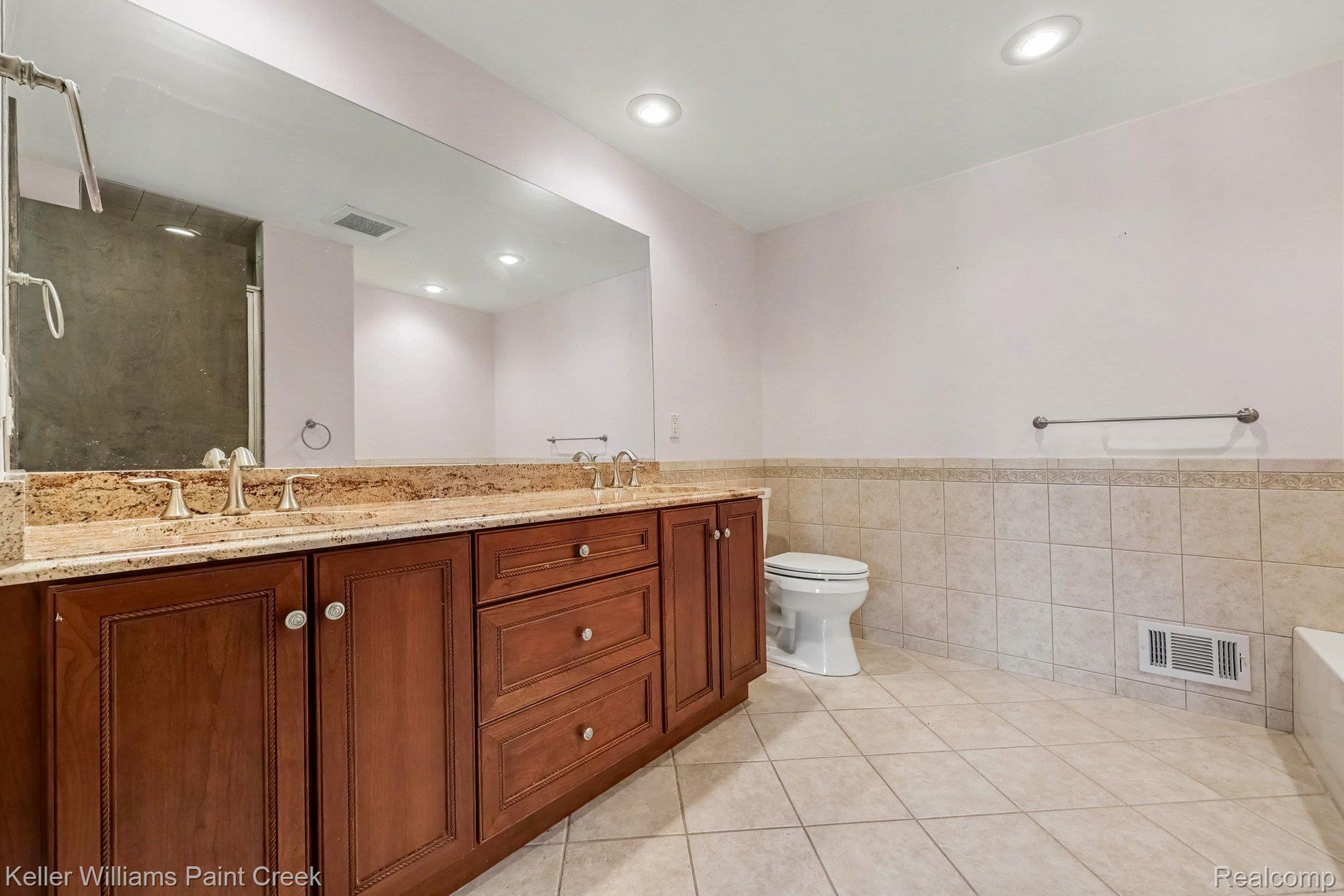 2717 Powderhorn Ridge Road Rochester, MI 48309 - Photo 24 of 48 Dual vanity with a stone countertop, extensive wall-mounted mirror, recessed lighting, and a tiled shower enclosure