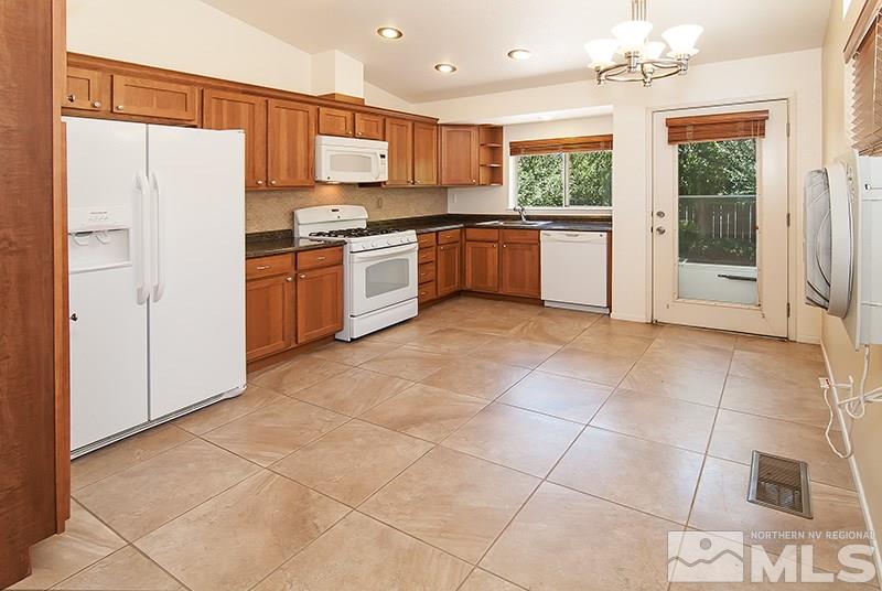 7716 Pickering Circle Reno, NV 89511 - Photo 2 of 15 a kitchen with granite countertop a refrigerator and a stove top oven