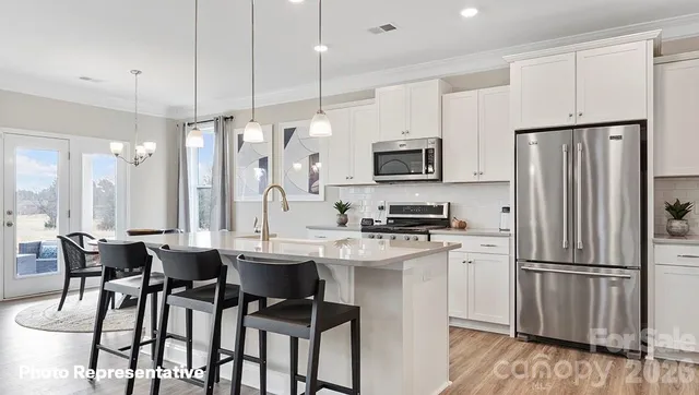 a kitchen with stainless steel appliances a dining table chairs refrigerator and microwave