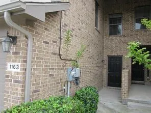 a brick building with a door and a yard