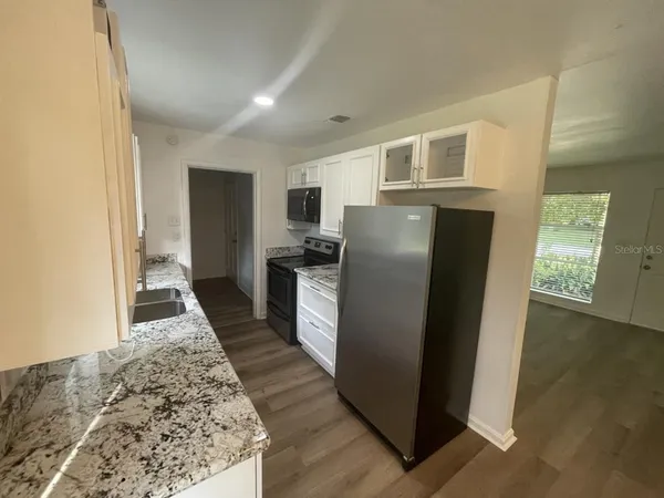 a kitchen with stainless steel appliances granite countertop a refrigerator a stove and a sink
