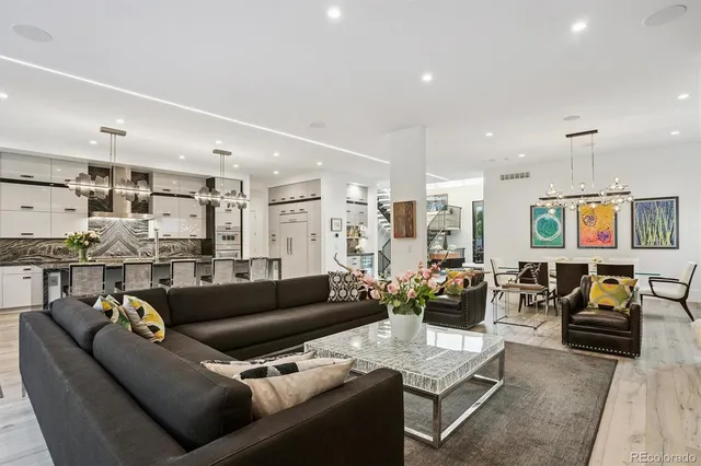 a living room with furniture kitchen view and a chandelier