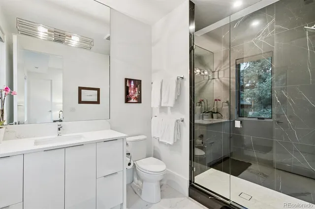 a bathroom with a shower sink vanity mirror and toilet