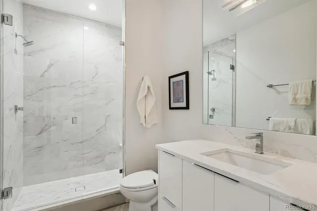 a bathroom with a granite countertop sink toilet and shower