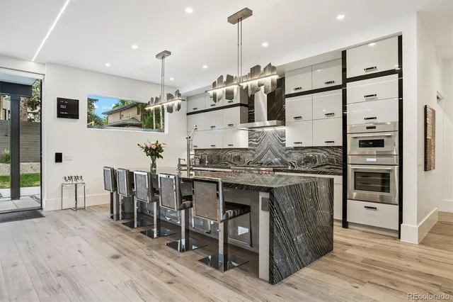 a kitchen with stainless steel appliances kitchen island granite countertop a table chairs and a refrigerator