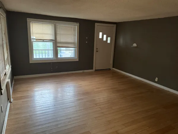 an empty room with wooden floor and windows