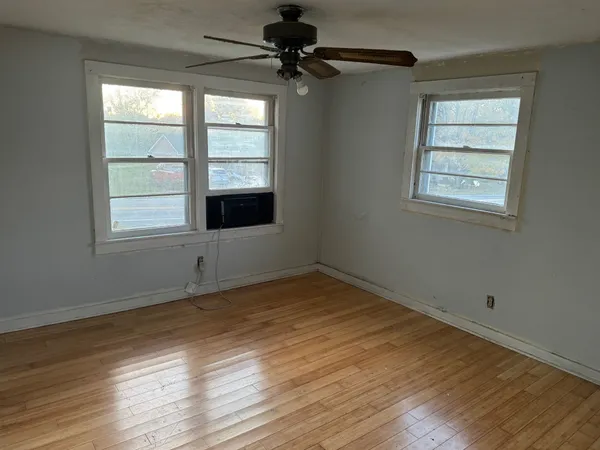 a view of an empty room with a window and wooden floor
