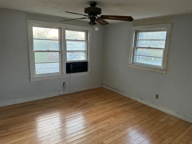 a view of an empty room with a window and wooden floor