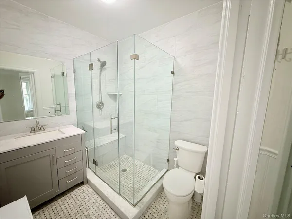 a bathroom with a shower sink vanity mirror and toilet