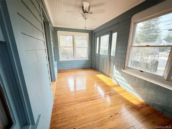 a view of empty room with wooden floor and fan