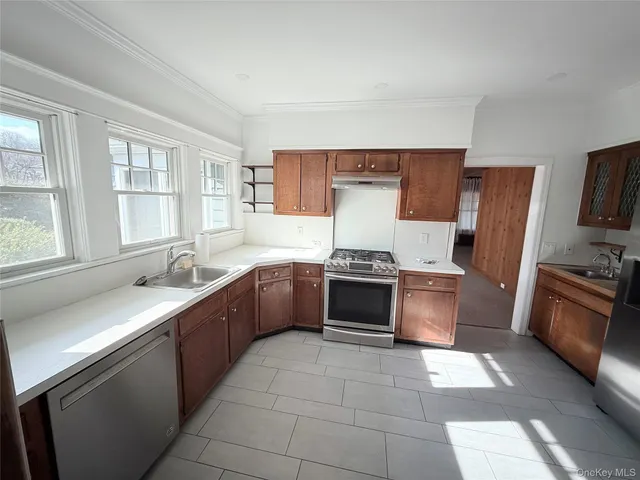 a large kitchen with stainless steel appliances granite countertop a stove a sink and a refrigerator