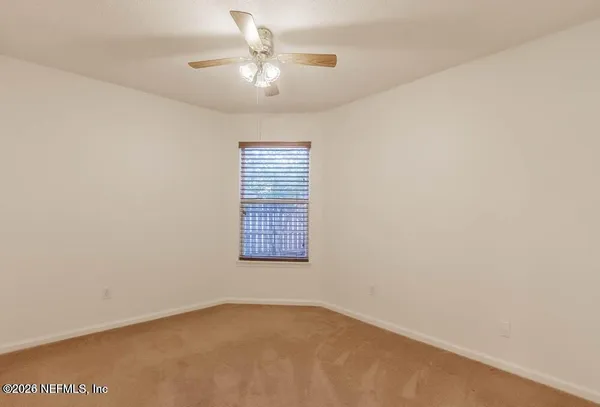 an empty room with windows and fan
