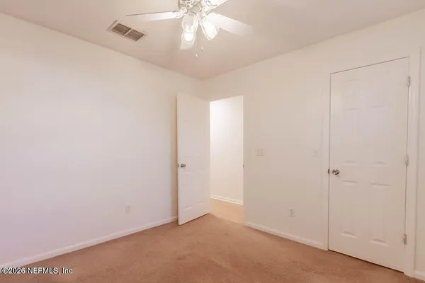 an empty room with a chandelier fan and windows