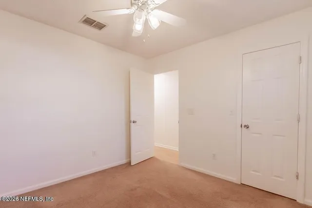 an empty room with a chandelier fan and windows
