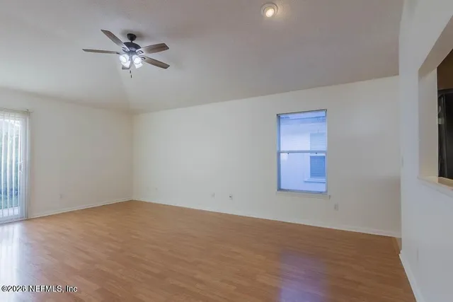 a view of an empty room with a window and wooden floor