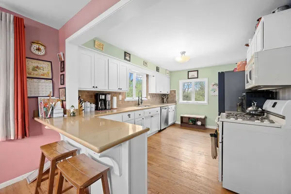 a kitchen with granite countertop white cabinets white appliances a sink and a large window