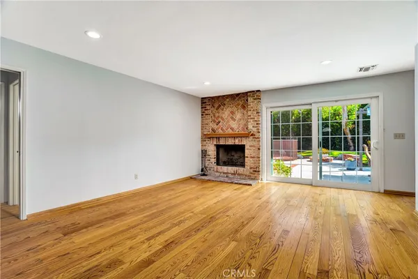 a view of empty room with wooden floor and fireplace