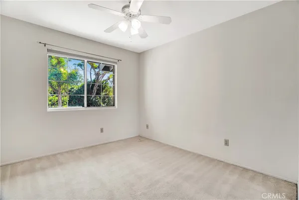 an empty room with a window and a ceiling fan