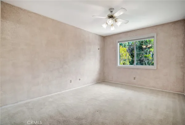 an empty room with a chandelier fan and windows