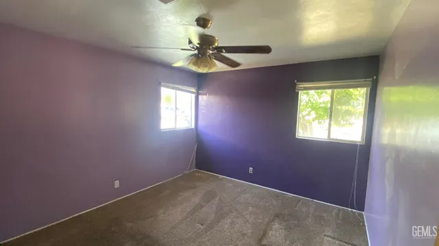 en empty room with windows and chandelier fan