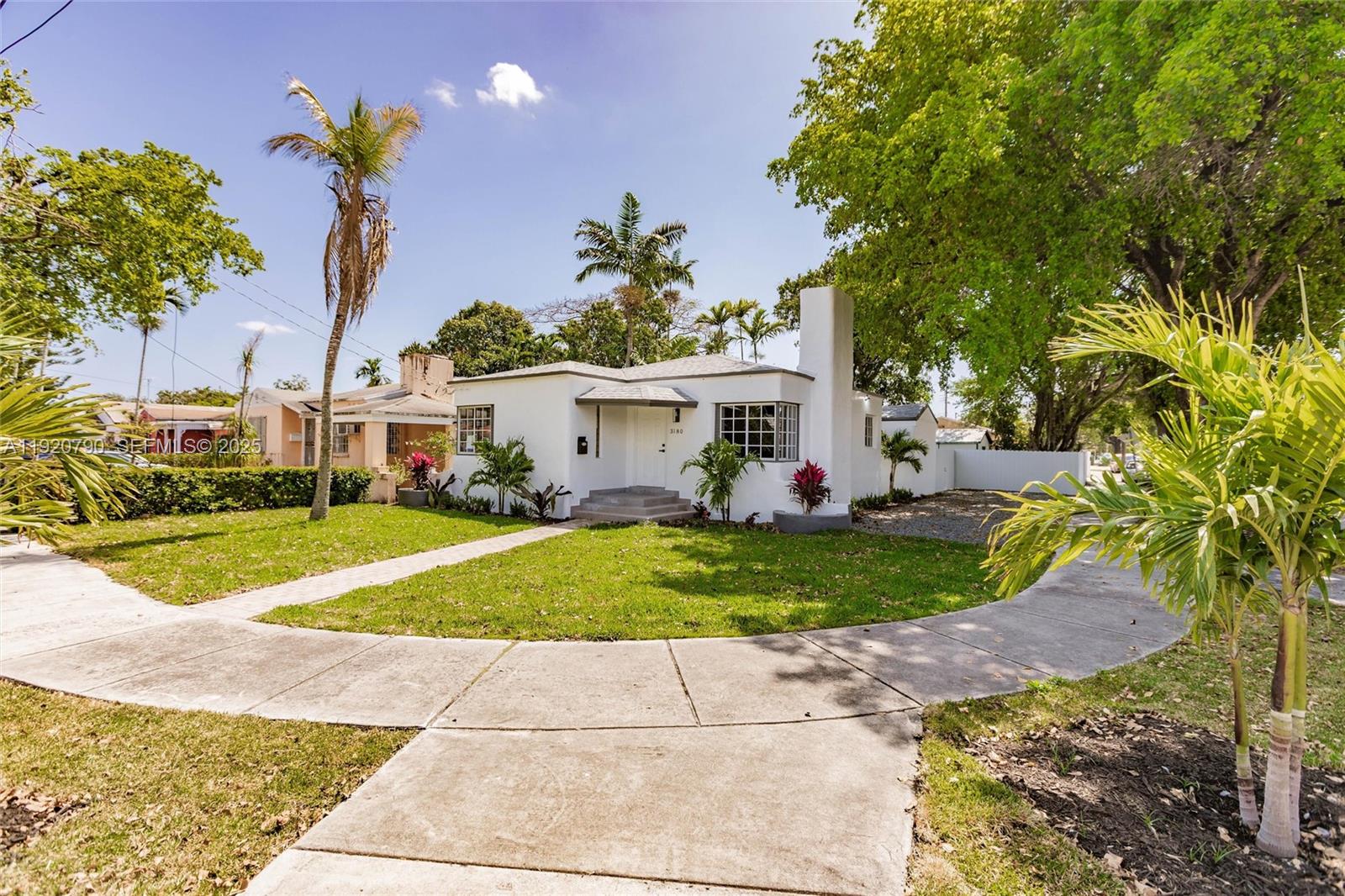 3180 Northwest 2nd Street Miami, FL 33125 - Photo 1 of 29 a view of a white house with a yard and potted plants