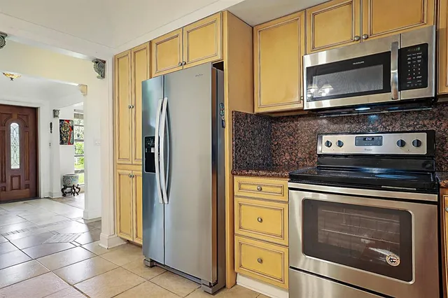 a kitchen with stainless steel appliances granite countertop a refrigerator a stove and a sink with wooden floor