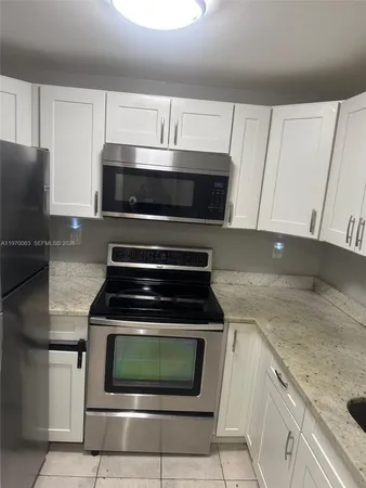 a kitchen with granite countertop white cabinets and black stainless steel appliances