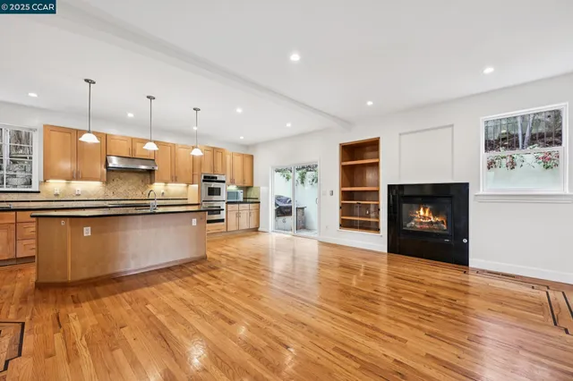 a large kitchen with stainless steel appliances kitchen island granite countertop a refrigerator a stove a sink and a wooden floors