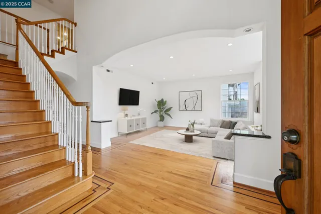 a living room with couches and a flat screen tv with kitchen view