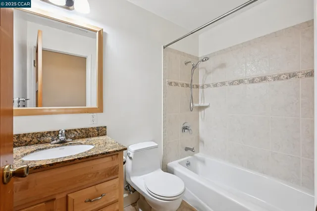 a bathroom with a granite countertop sink toilet a mirror and shower