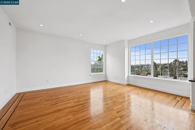 a view of an empty room with a window and wooden floor