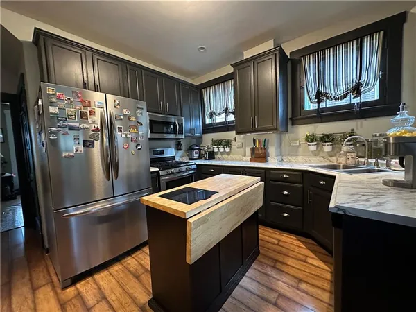 a kitchen with granite countertop stainless steel appliances a sink refrigerator and microwave